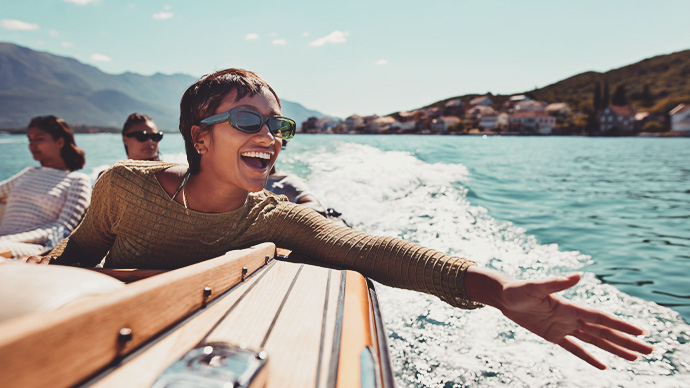 Cheerful young woman enjoying motorboat ride with friends on sunny day