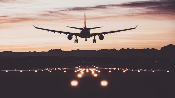 An airplane moments from touching down on the runway at sunrise.