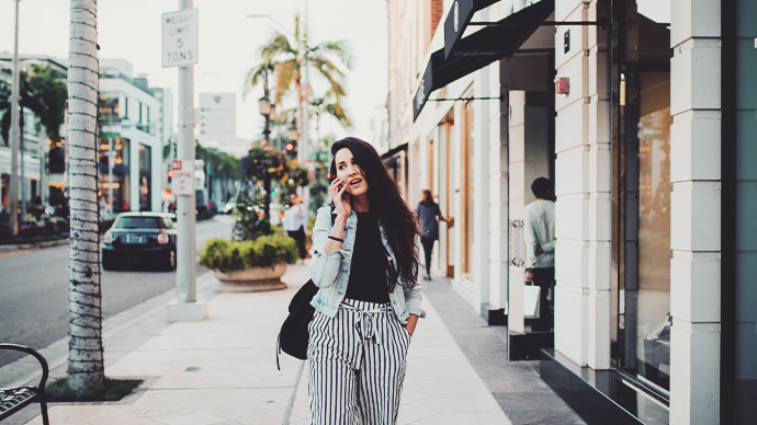 Young woman walking the streets of Los Angeles - West Hollywood - Beverly Hills area, talking on her cellphone, enjoying the beautiful, sunny day.