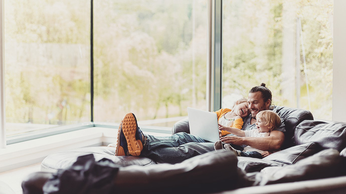 Happy father with two children looking at laptop on the couch