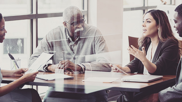 Mid adult Hispanic woman gestures as she discusses something with a lawyer. The woman is sitting next to her husband and father-in-law.