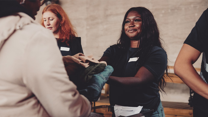 Smiling volunteer giving clothes to homeless woman at community center