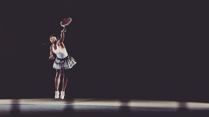 Female black tennis player hitting a serve during a tennis match, shot against a black back drop, March 3rd 2020.