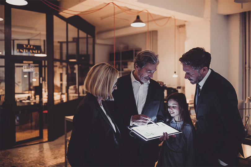 Business people and girl looking at shining tablet in office