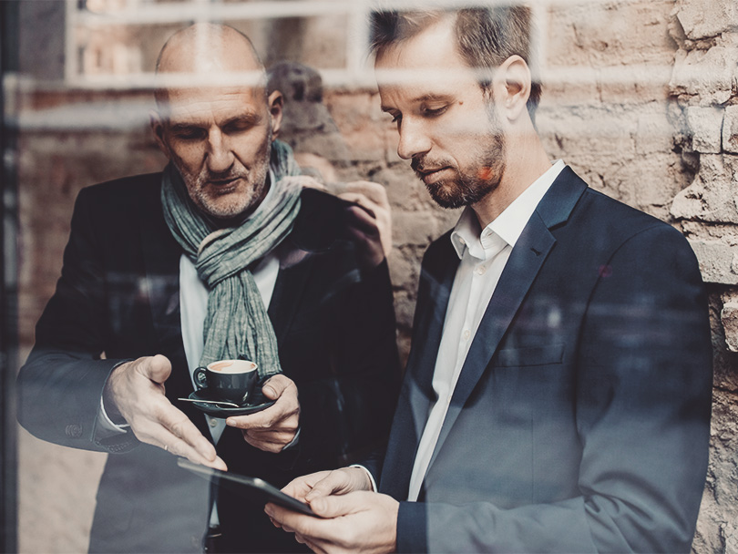 Senior and mid-adult businessman sharing a tablet