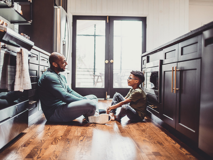 Father talking with tween son in residential kitchen